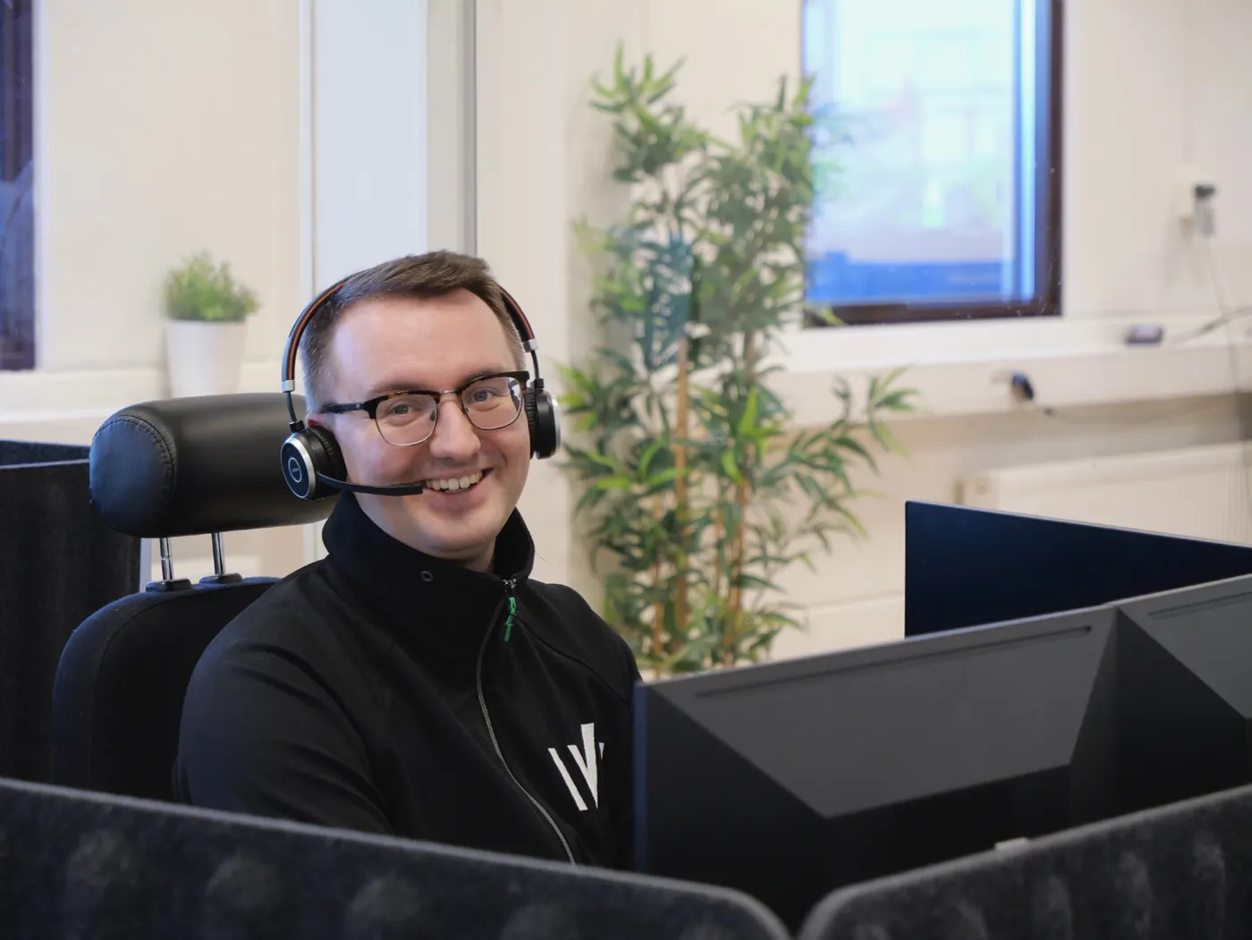 Leende supportmedarbetare på Crona med headset vid sin arbetsplats