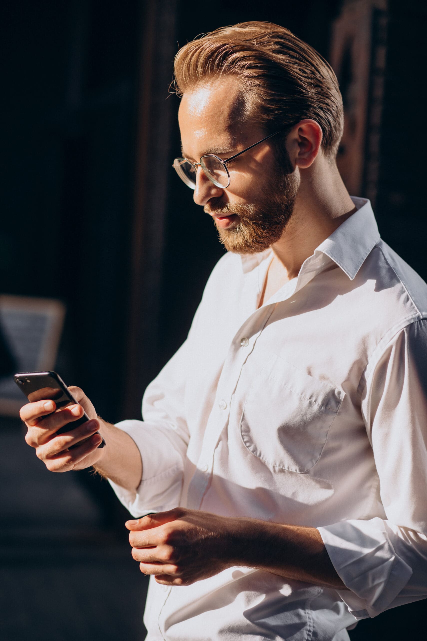 Young bearded man using phone and walking at the street